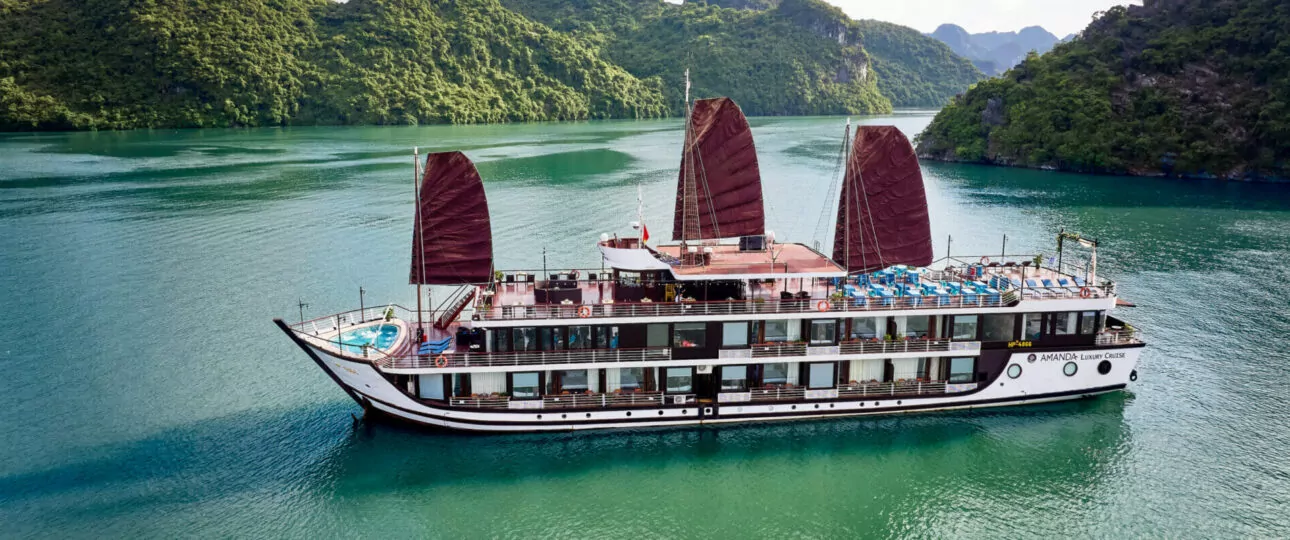 Amanda Luxury Cruise sailing through Lan Ha Bay with traditional maroon sails and bow pool