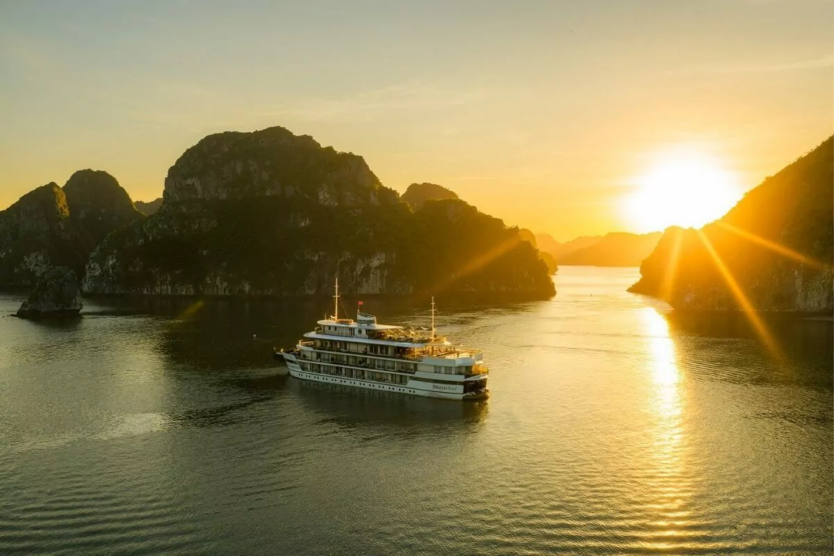 Luxury boutique cruise sailing through Bai Tu Long Bay at sunset — Vietnam's most exclusive and uncrowded UNESCO bay, 2026