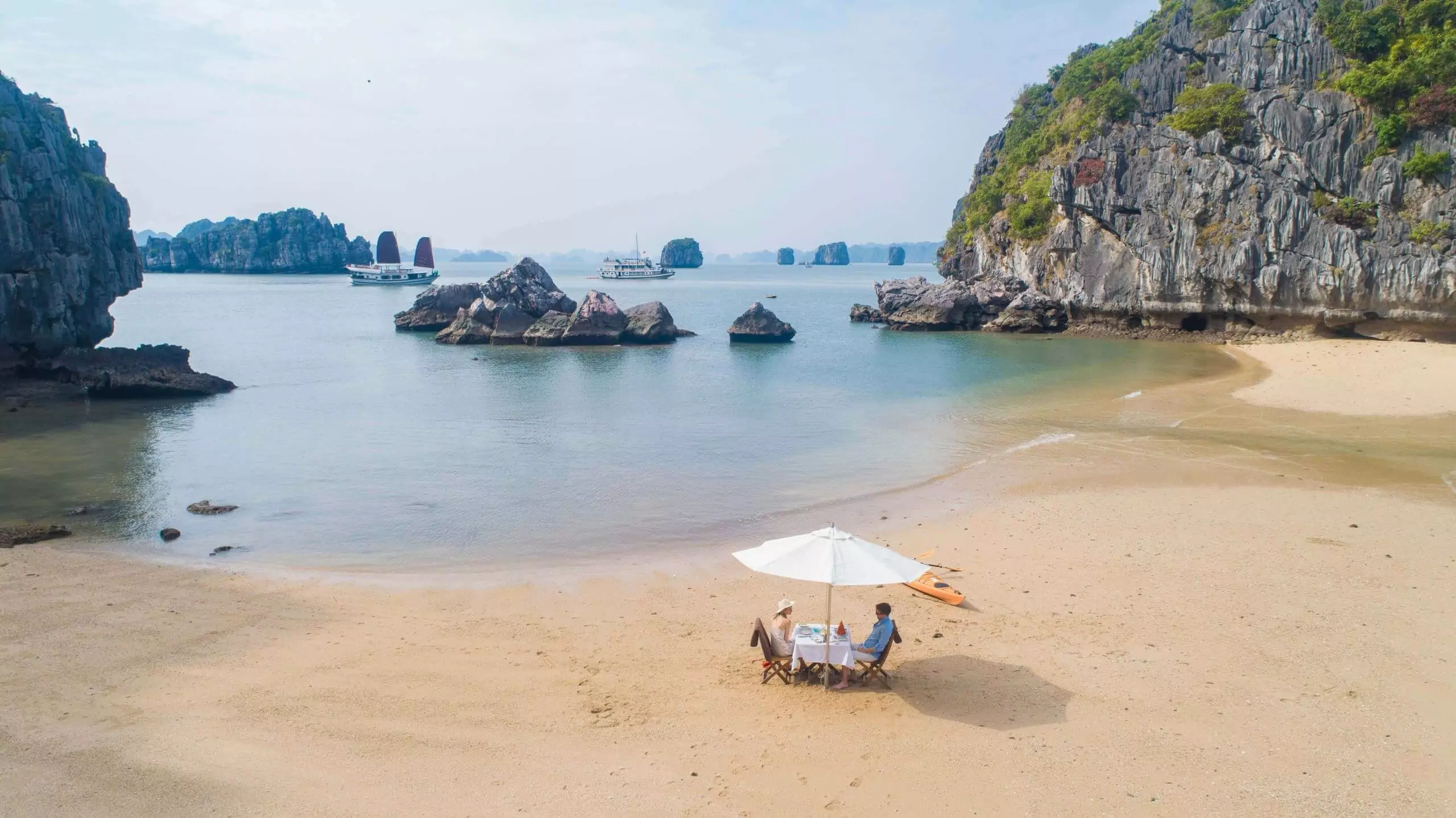Ban Chan Beach — pristine white sand and clear water surrounded by limestone cliffs, Bai Tu Long Bay's signature beach, Vietnam