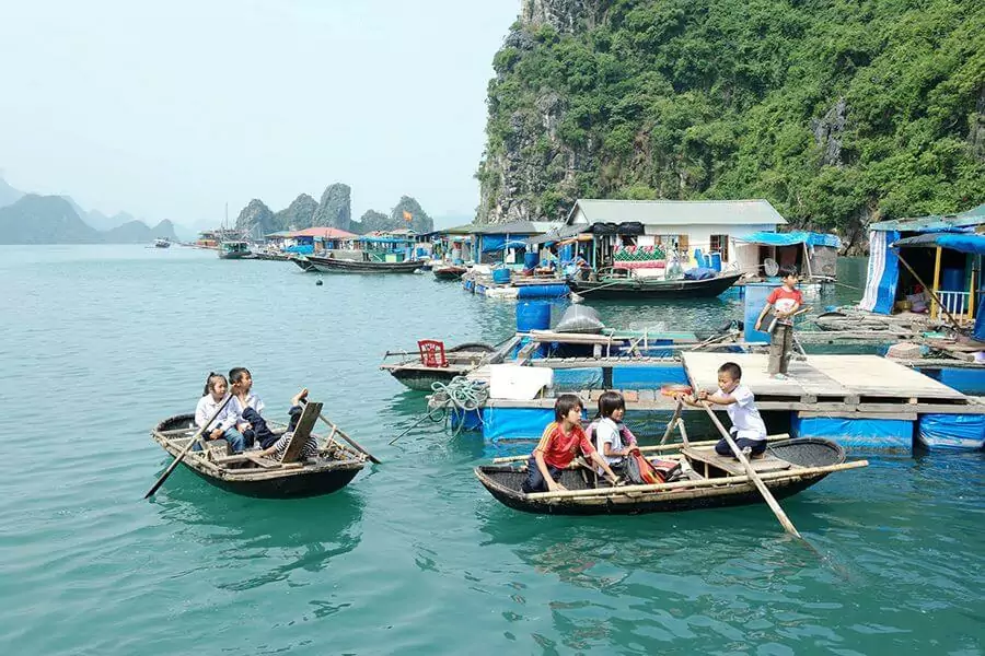 Children rowing to Halong Bay's first floating school at Cua Van Fishing Village — a defining image of life in Vietnam's largest floating community