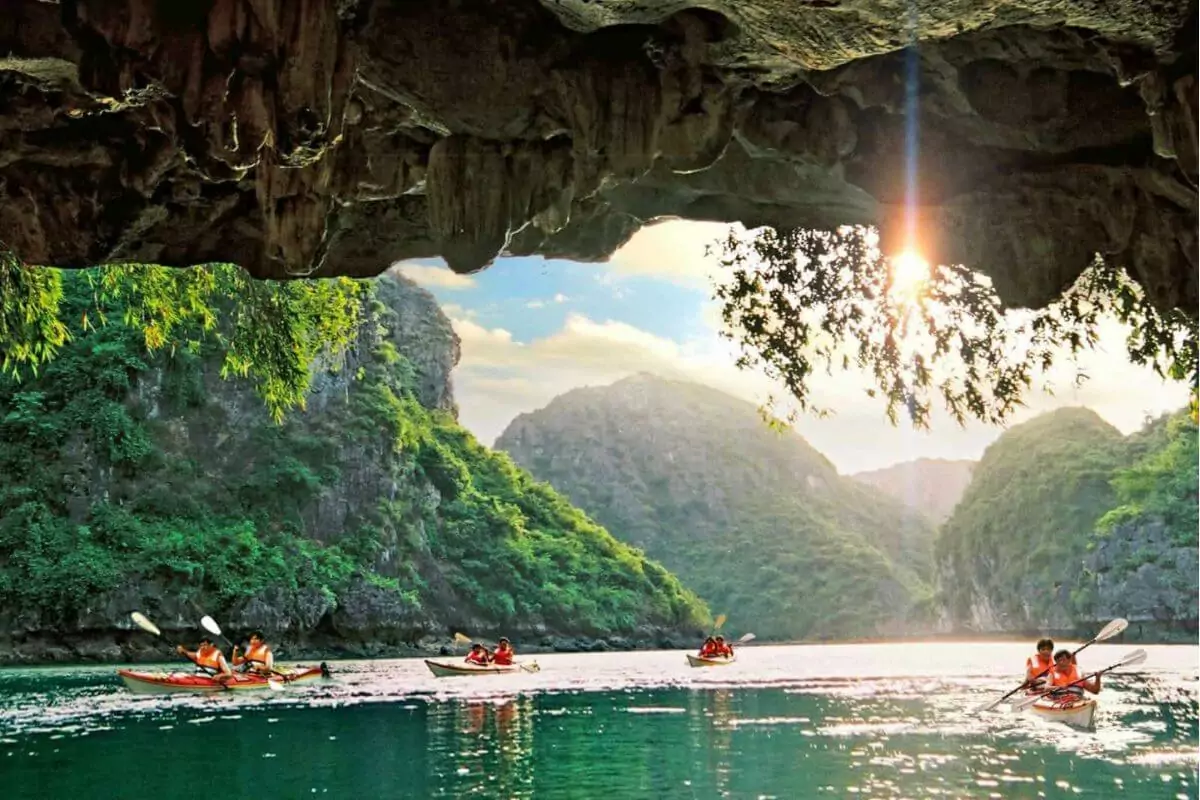 Kayaking through Dark and Bright Cave from the dark tunnel into the sunlit hidden lagoon, Lan Ha Bay's most iconic attraction, Vietnam