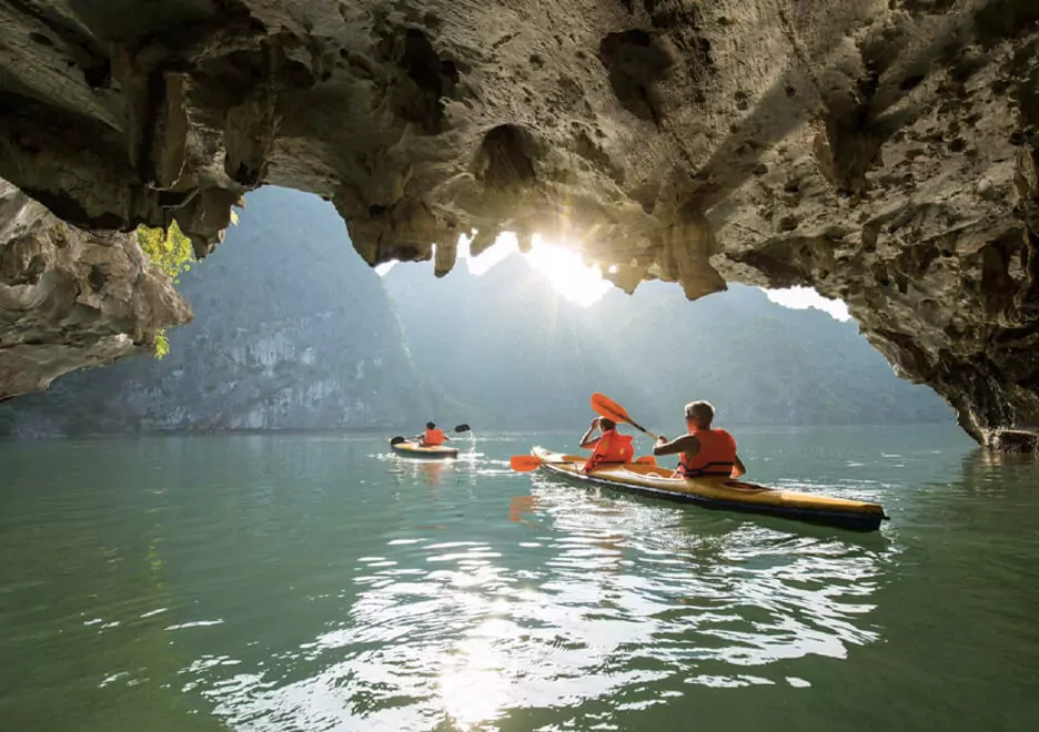 Bright Cave interior — natural sunlight filtering through limestone cracks illuminates the emerald water below, Dark and Bright Cave, Lan Ha Bay Vietnam
