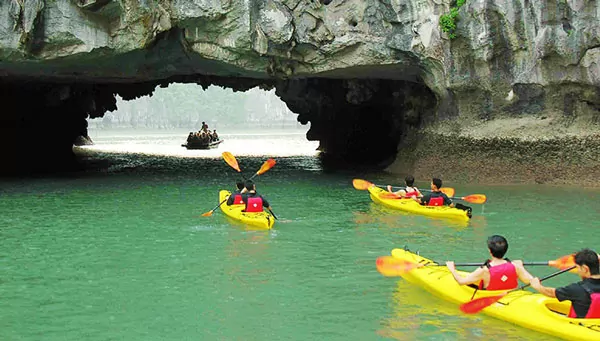 Kayaking through Luon Cave's natural limestone arch into the hidden emerald lagoon — Halong Bay's most iconic active experience, Vietnam