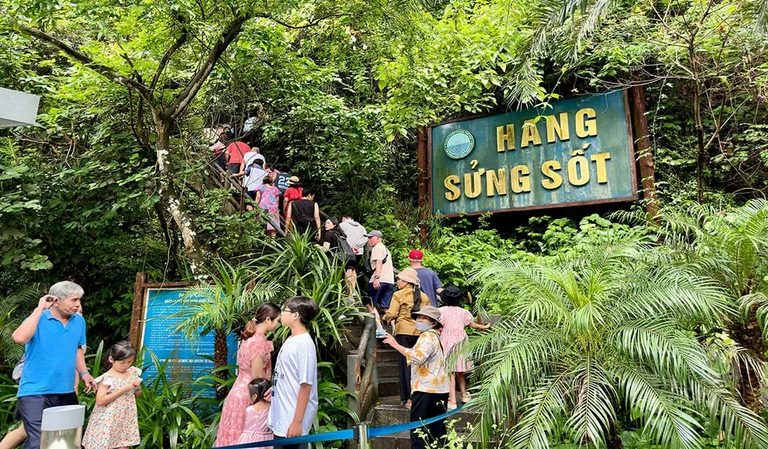 Stone steps leading up to Sung Sot Cave entrance through lush forest canopy on Bo Hon Island, Halong Bay Vietnam