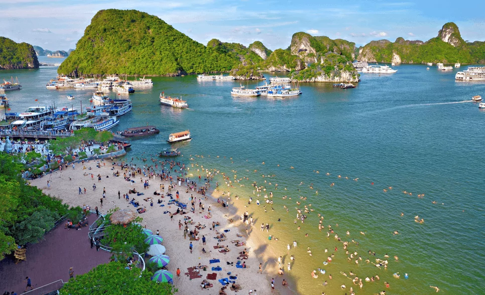 Swimming and relaxing at Ti Top Island beach (Vang Trang Beach) with kayaks and limestone cliffs of Halong Bay in the background, Vietnam