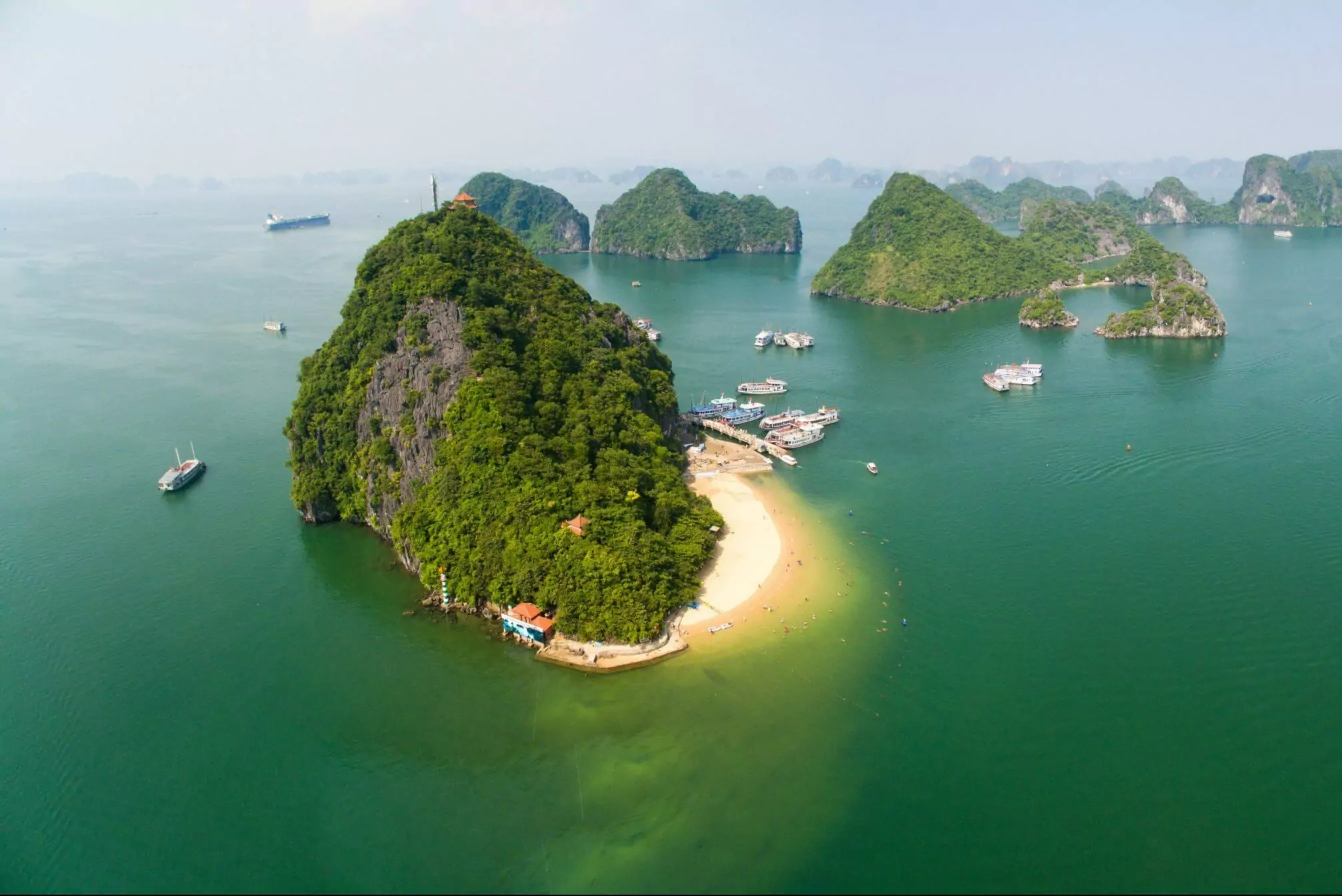 Halong Bay cruise boat approaching Ti Top Island — limestone mountain rising from emerald waters, Halong Bay Vietnam