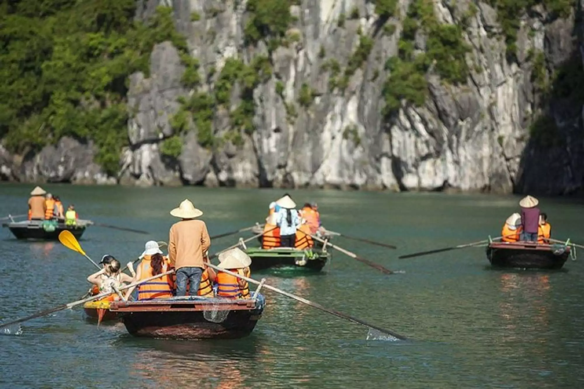 Bamboo boat passing through the natural limestone arch of Cao Cave, the gateway to Vung Vieng Fishing Village, Bai Tu Long Bay Vietnam