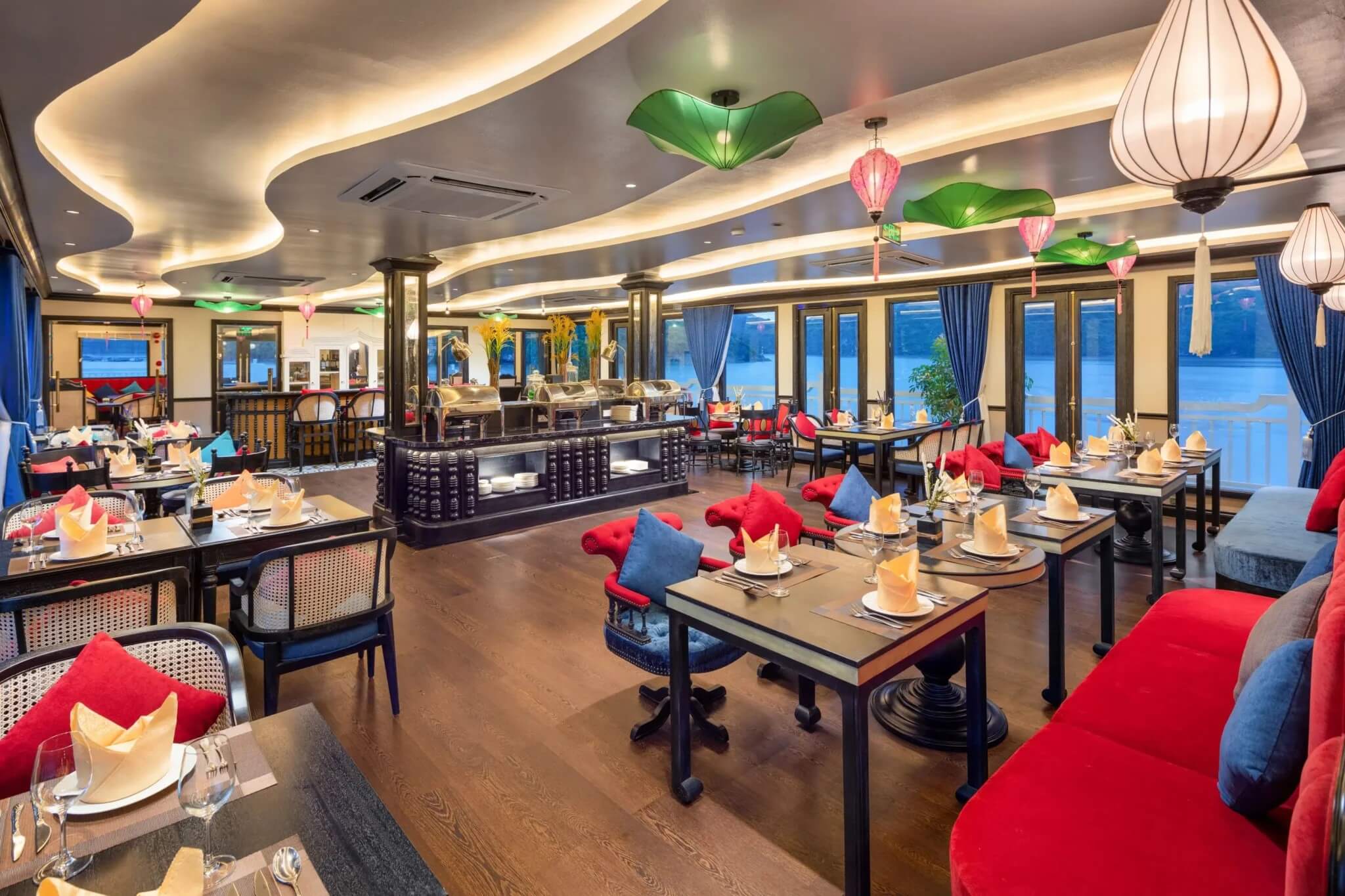 Aurora Cruise restaurant dining hall set for dinner with lantern lighting and bay views, Lan Ha Bay