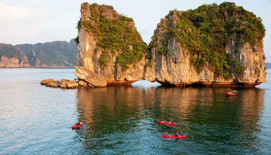 Tourists kayaking between limestone karsts in Halong Bay during summer