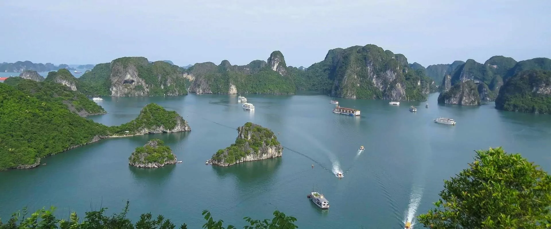 Cruise boat sailing through Halong Bay limestone islands on a misty morning