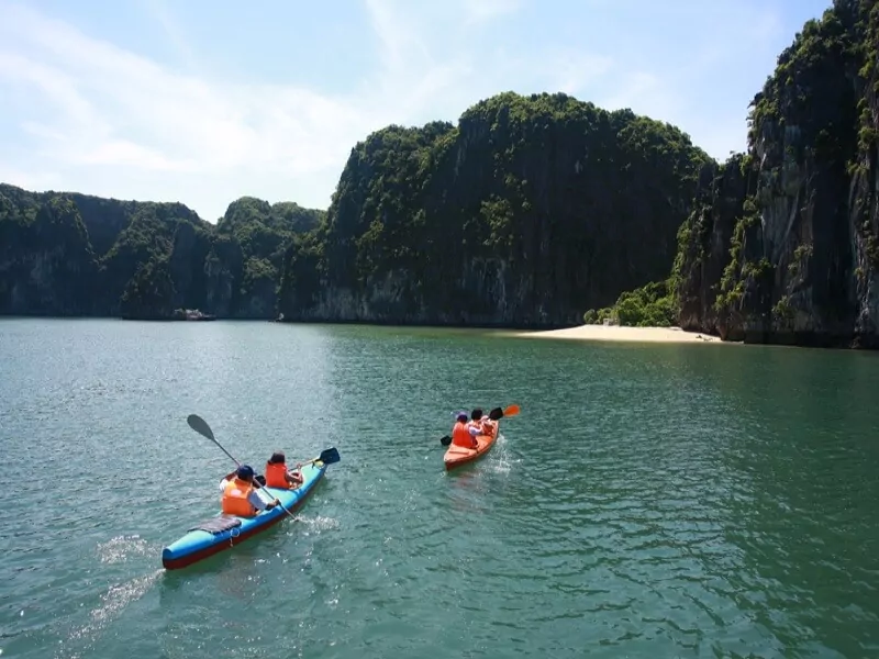 Tourists kayaking near a white sand beach in Lan Ha Bay, Cat Ba Archipelago