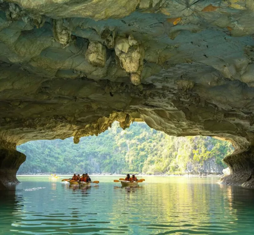 Kayaking through Luon Cave's 60-meter limestone tunnel into the hidden lagoon, Halong Bay's iconic kayaking experience, Vietnam