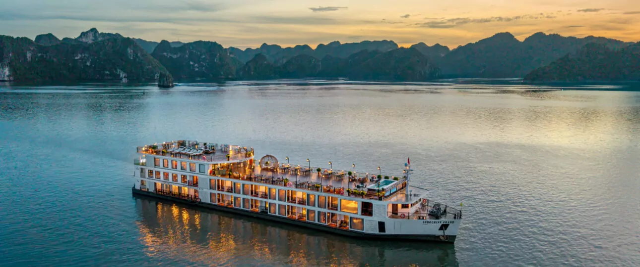 Aerial view of Indochine Grand Cruise sailing through Halong Bay at sunset