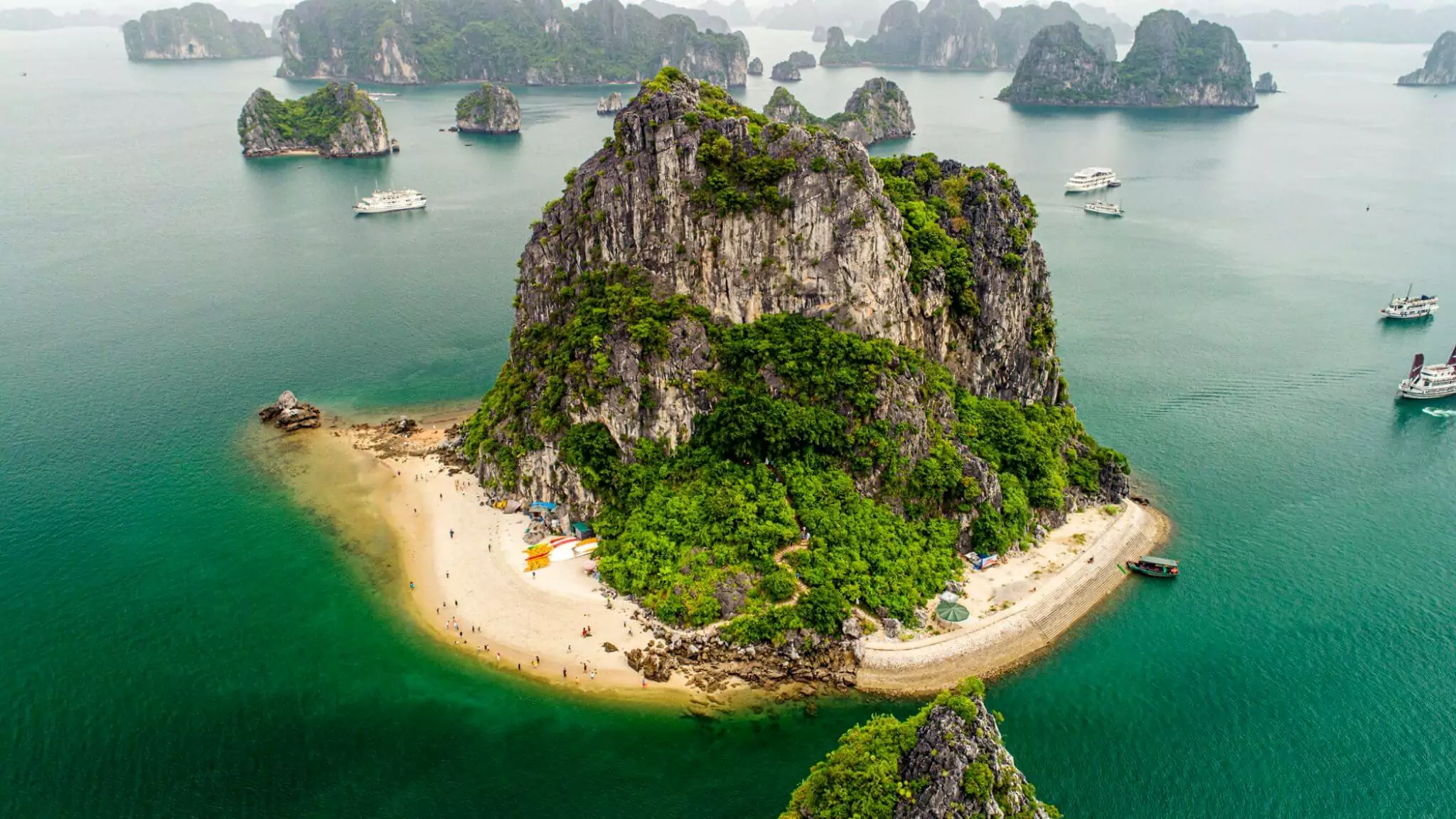 Secluded white-sand beach at the base of Hon Co Island below Thien Canh Son Cave, Bai Tu Long Bay Vietnam