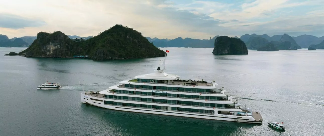 Catherine Cruise Halong Bay exterior sailing past limestone karsts with tender boat alongside