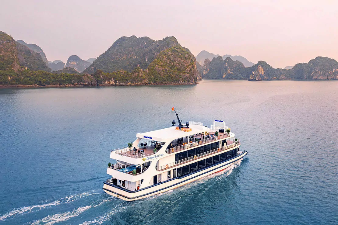 Diamond Era Cruise cruising through Halong Bay at sunset