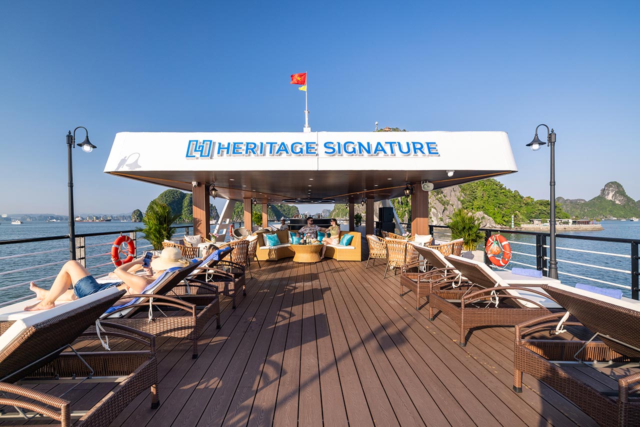 Sundeck lounge chairs beneath the Heritage Signature sign, Halong Heritage Signature Day Cruise