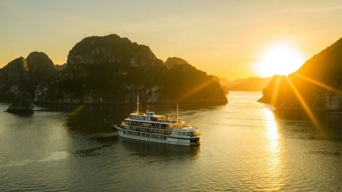 Luxury boutique cruise sailing through Bai Tu Long Bay at sunset — Vietnam's most exclusive and uncrowded UNESCO bay, 2026