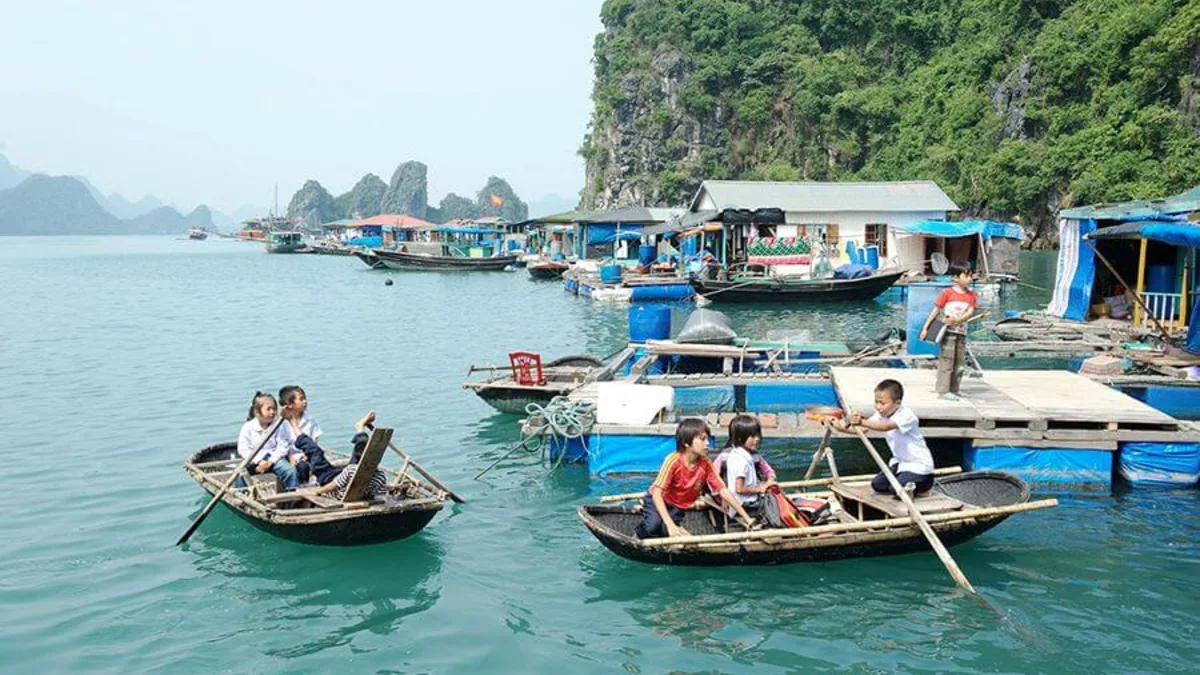 Children rowing to Halong Bay's first floating school at Cua Van Fishing Village — a defining image of life in Vietnam's largest floating community