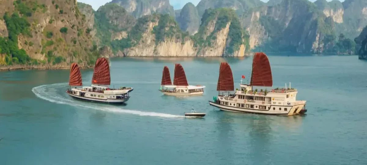 Halong Bay day cruise vs overnight cruise: a junk-style cruise ship at sunset among limestone islands