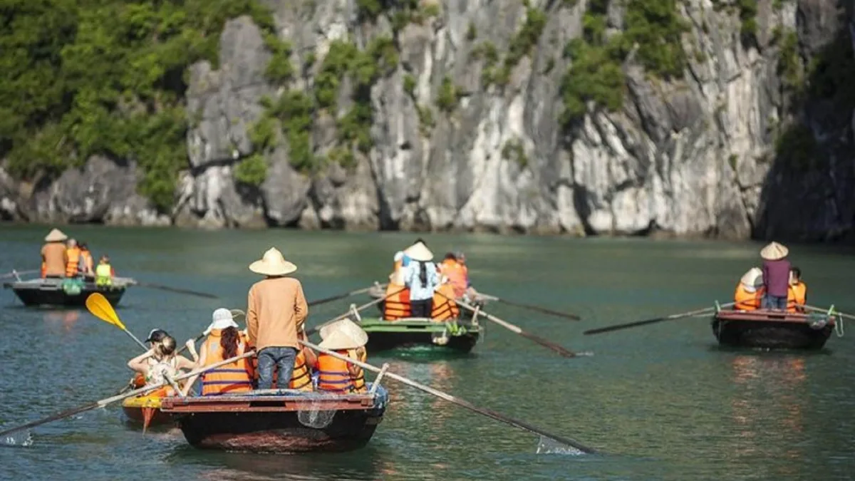 Bamboo boat passing through the natural limestone arch of Cao Cave, the gateway to Vung Vieng Fishing Village, Bai Tu Long Bay Vietnam